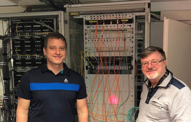Erik Schönau (Technische Dienste der Stadt Marburg) und Rudolf Herres (Fiber-Optics)  vor dem mittels AROONA STAR „aufgemotzten“ Datenschrank